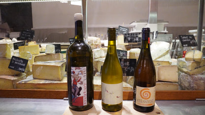 Cheese and wine tasting in Nice with French wine bottles and artisan cheeses displayed inside a traditional local fromagerie.