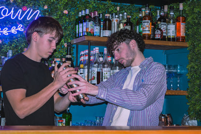 Team building cocktail class in Nice with group learning mixology techniques in a vibrant local bar setting.